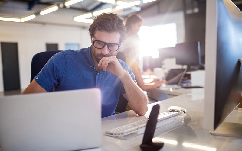 Ensure continuous protection Businessman on desktop and laptop device in open office