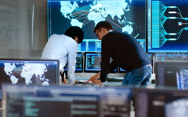 Two men working on computer in security operations room