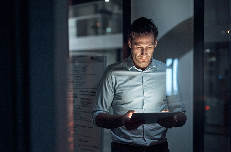 business-man-using-tablet-in-office-night