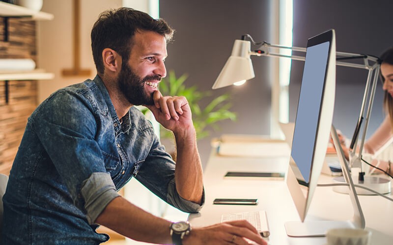 Man working on desktop smiling