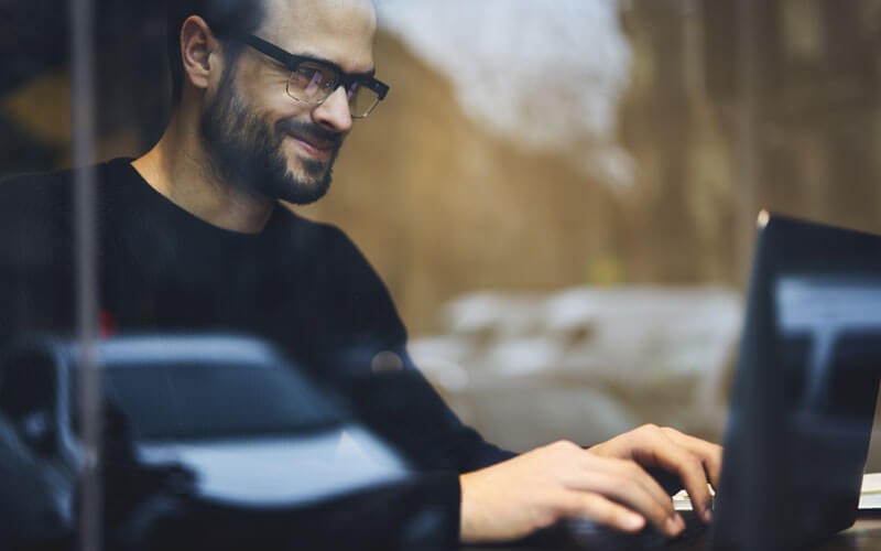 Take advantage of intuitive navigation and support Smiling man in glasses works on laptop computer