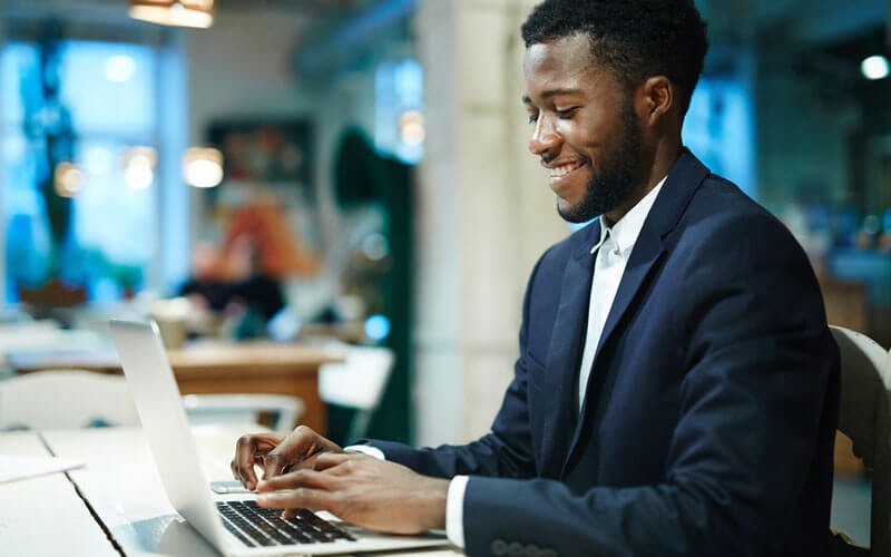 Smiling businessman on laptop computer in open office