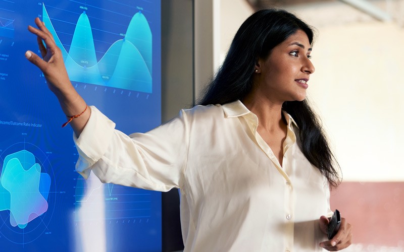 Businesswoman using a Ricoh interactive display to present in team meeting