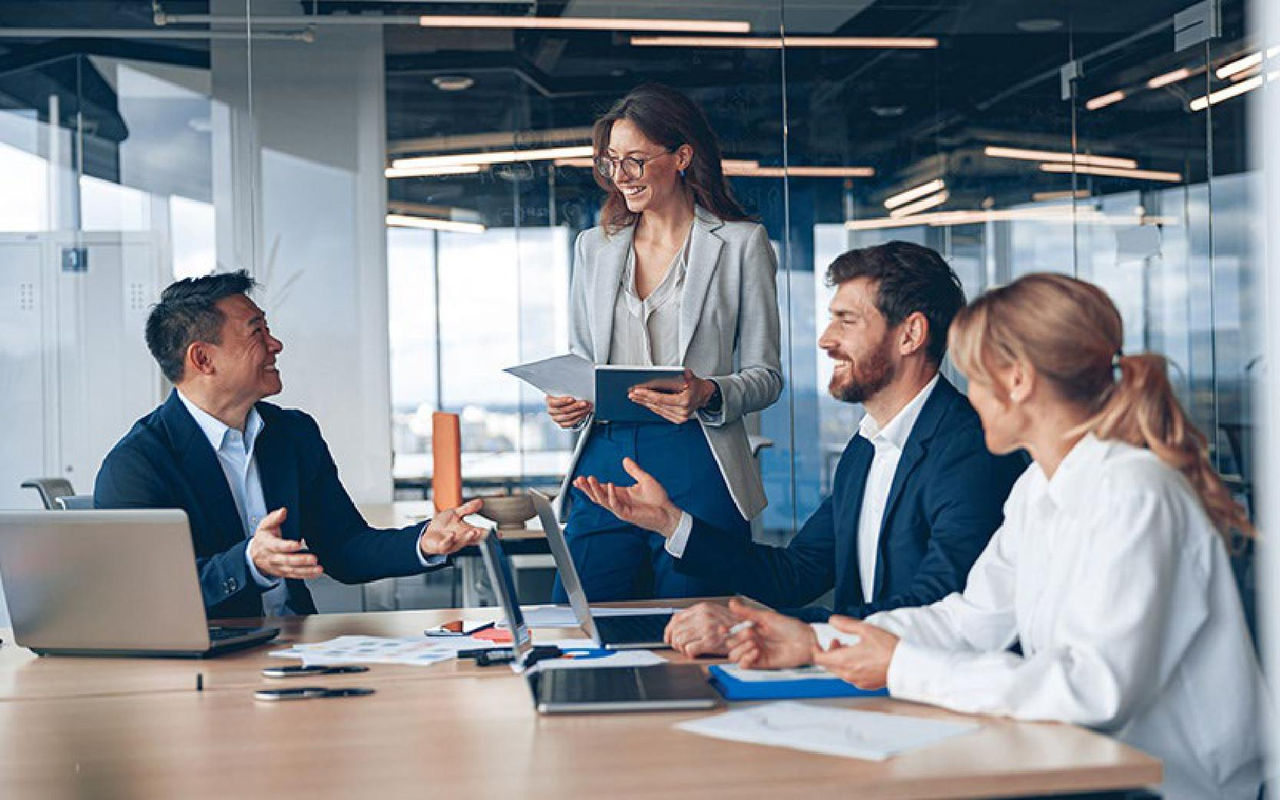 Team collaborates around table with smart devices, tablets and notebook computers