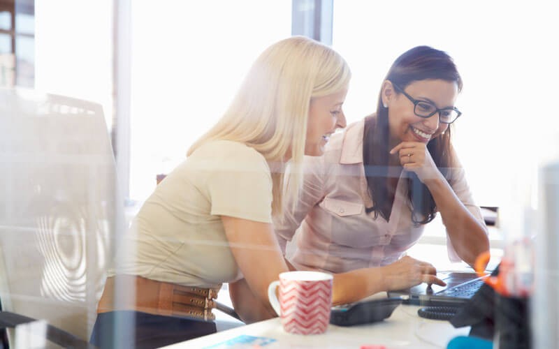 Two women looking at laptop smiling