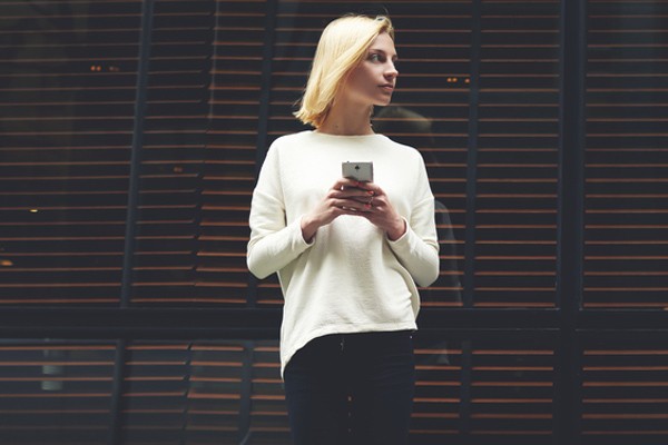 Woman on phone leaning against glass window 