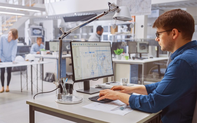 Businessman using CAD software on computer in open office