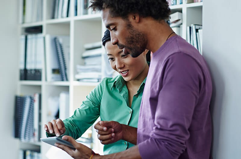 Smiling business teammates work at desks with computers